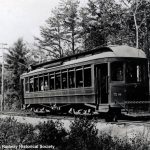 conductor standing in front of his trolley car in black and white